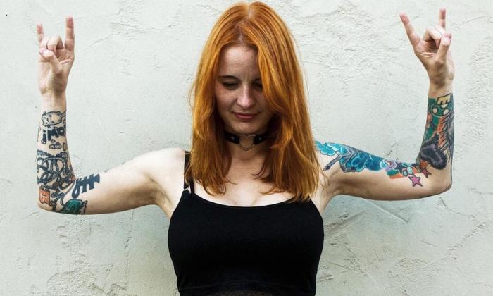 woman red hair tattoos on arms up in air