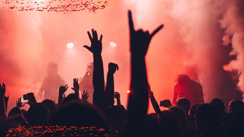 concert silhouette hands in air, red lights